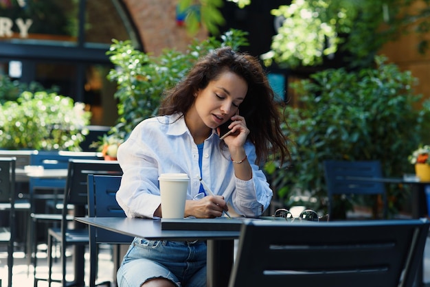 Mulher com café trabalhando no café ao ar livre de manhã