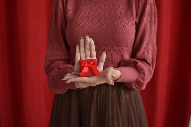 mulher com caixa de presente em fundo vermelho