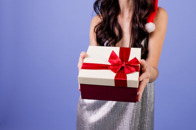 Mulher com caixa de presente, usando chapéu de Natal isolado sobre roxo