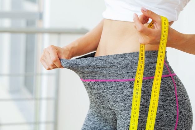 Mulher com calças grandes após a perda de peso, o conceito de dieta.