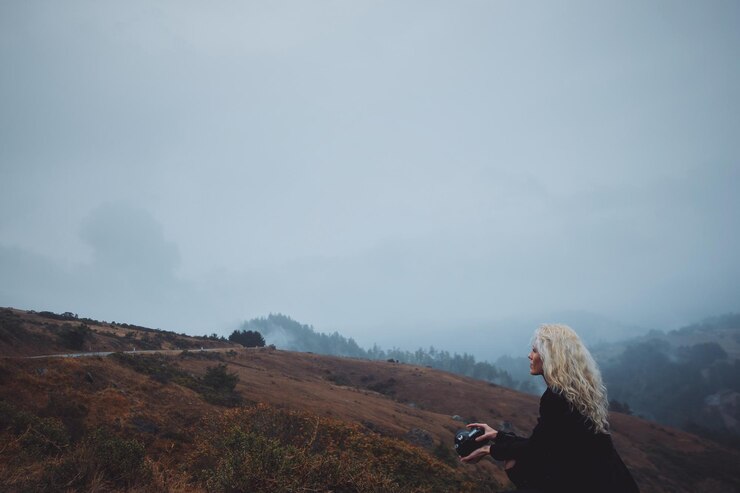 Foto mulher com câmera em paisagem contra o céu