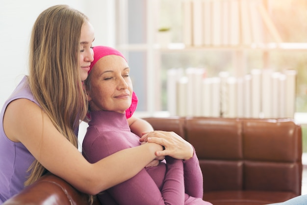 Foto mulher com câncer deitada, apoiada pela mãe em casa. conceito de confiança e ética