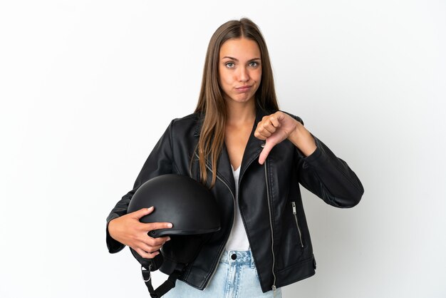 Mulher com capacete de motociclista sobre fundo branco isolado, mostrando o polegar para baixo com expressão negativa