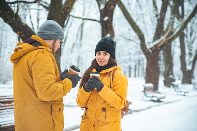 Mulher com cara acumulada conversando com homem. tomando café para viagem. conceito de parque da cidade de inverno nevado