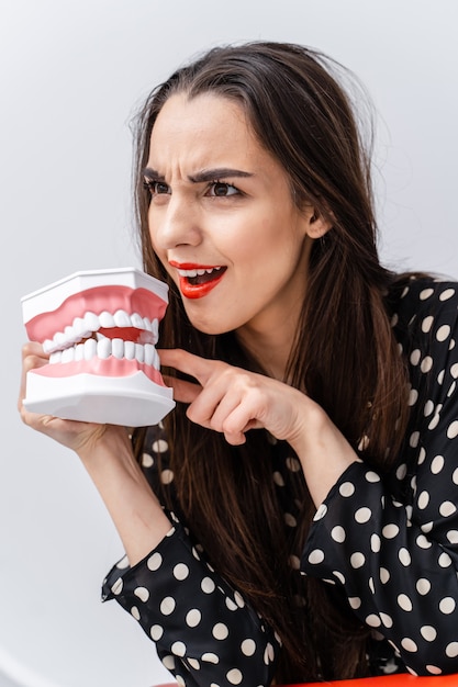 Mulher com cara de surpresa e boca aberta. Jovem, segurando a mandíbula educacional do dentista aberto perto do rosto. Conceito odontológico. Emoções engraçadas.