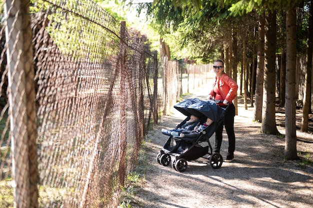 Mulher com carrinho de bebê caminha no parque