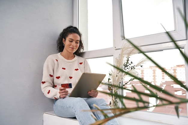 Mulher com cartão de crédito e tablet comprando na internet, compras online