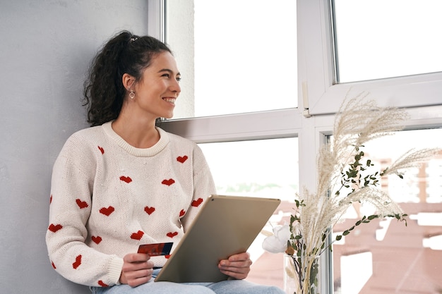 Mulher com cartão de crédito e tablet comprando na internet, compras online