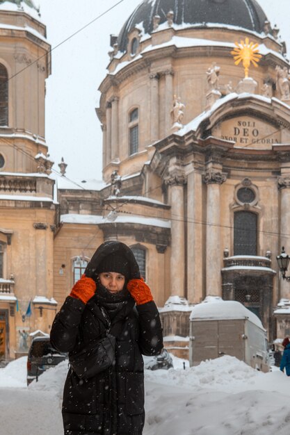 Mulher com casaco de inverno caminhando pela calçada da cidade após uma tempestade de neve