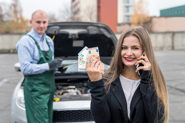 Mulher com celular, carro e mecânico