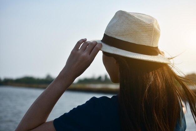 Mulher com chapéu contra o lago