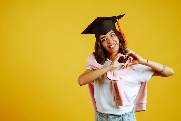 Mulher com chapéu de formatura fazendo sinal de amor