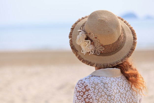 Mulher com chapéu de luxo olhando para o mar