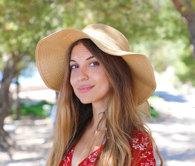 Mulher com chapéu de palha de verão sorrindo e olhando para você