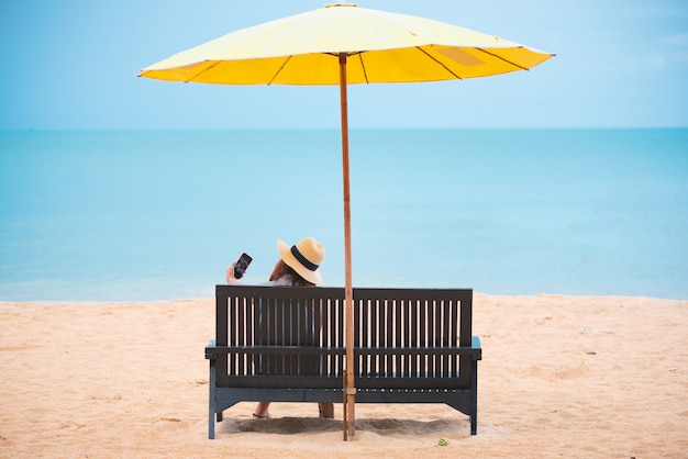 Mulher com chapéu de palha que relaxa na praia.