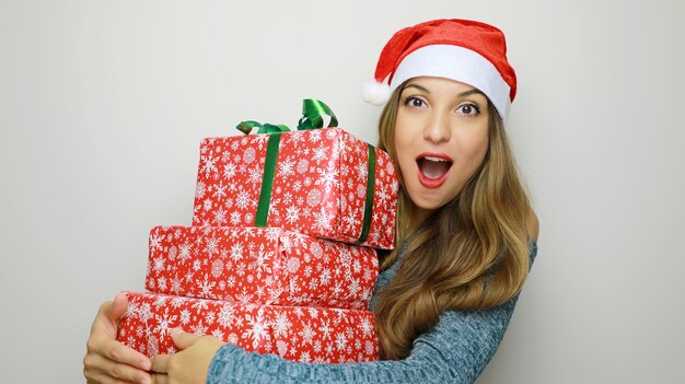 Mulher com chapéu de Papai Noel com caixa de presentes sobre fundo branco