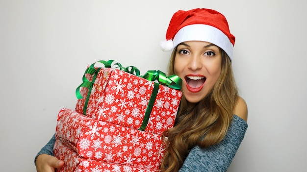 Mulher com chapéu de Papai Noel com presentes de Natal nas mãos