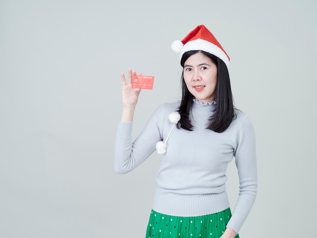 Mulher com chapéu de Papai Noel na mão mostrando compras com cartões de crédito