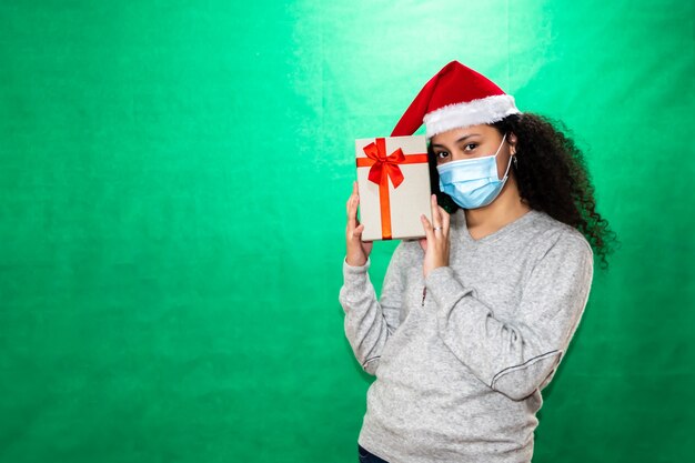 Mulher com chapéu de Papai Noel segurando presentes de vários tamanhos