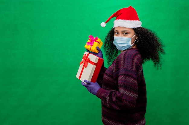 Mulher com chapéu de Papai Noel segurando presentes de vários tamanhos