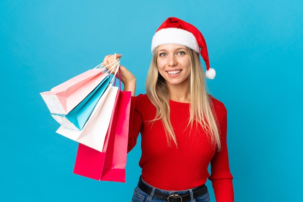 mulher com chapéu de Papai Noel segurando sacolas de compras