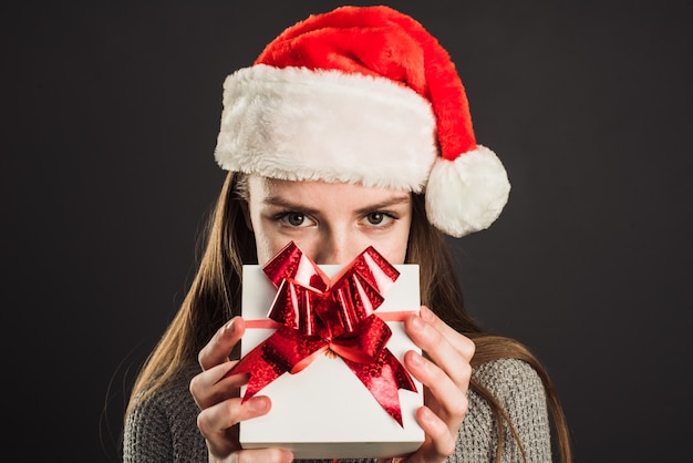 Mulher com chapéu de Papai Noel segurando um presente de Natal