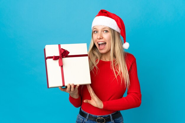 mulher com chapéu de Papai Noel segurando uma caixa de presente