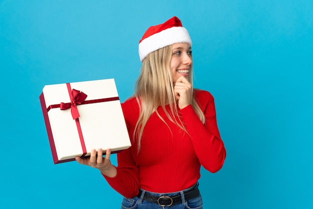 mulher com chapéu de Papai Noel segurando uma caixa de presente