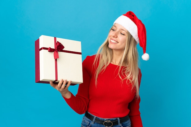 mulher com chapéu de Papai Noel segurando uma caixa de presente