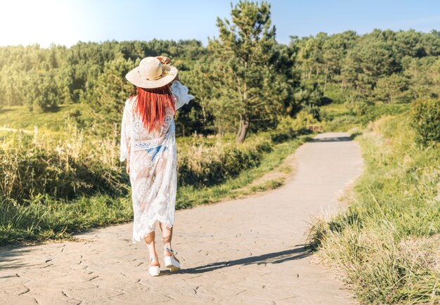 Mulher com chapéu e vestido branco andando