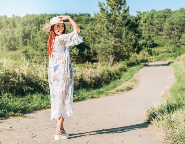 mulher com chapéu e vestido branco andando