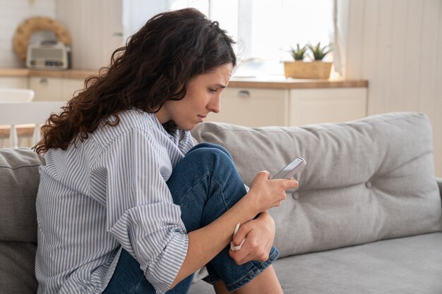 Mulher com ciúme lendo mensagem de texto com más notícias