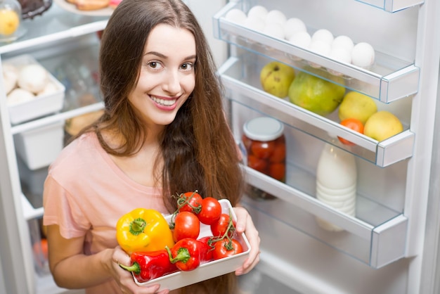 Mulher com comida perto de geladeira