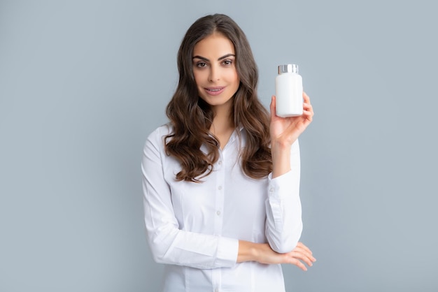 Foto mulher com comprimidos de garrafa mulher segurando o frasco de comprimidos de remédio branco sem rótulo cápsulas ou comprimidos de vitaminas medicina de farmácia e conceito de cuidados de saúde