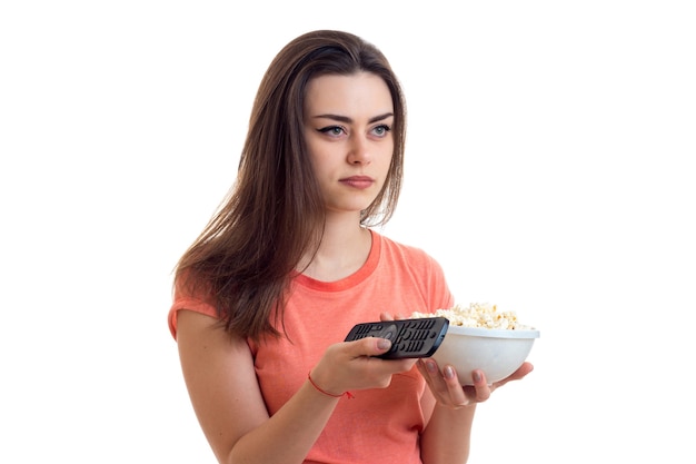 Mulher com controle remoto e pipoca assistindo a uma tv isolada no fundo branco