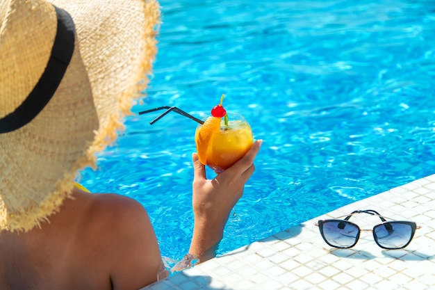 Mulher com coquetel à beira da piscina. Foco seletivo.