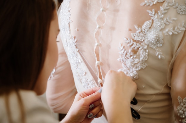 Mulher com costureira fazendo o toque final na loja de roupas de noiva