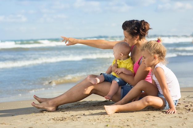 Mulher com crianças brincando na praia, mãe com uma criança e bebê na natureza