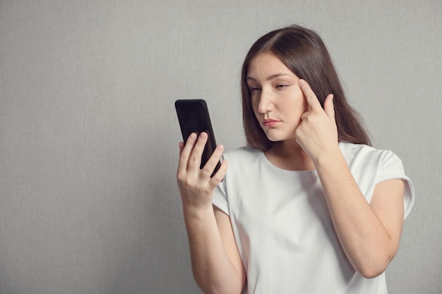 Mulher com deficiência visual olha atentamente para a tela do telefone