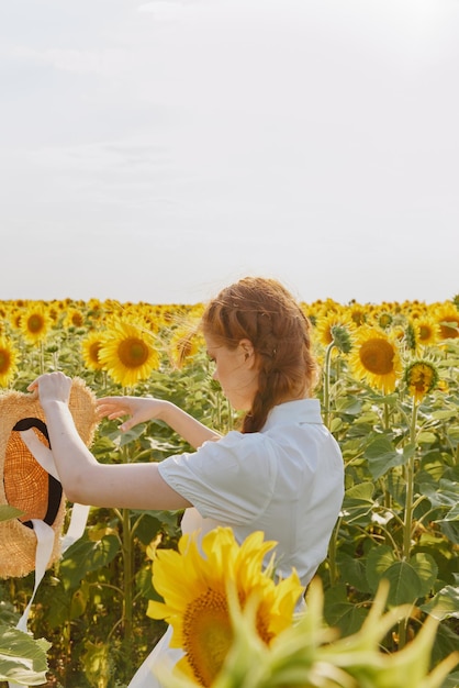 mulher com duas tranças em um chapéu de palha em um vestido branco um campo de girassóis agricultura tempo de verão foto de alta qualidade