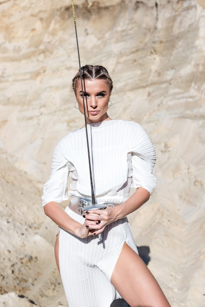 Foto mulher com espada em traje branco total no deserto