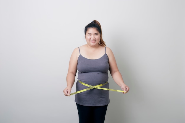 Mulher com excesso de peso, medindo sua barriga gorda