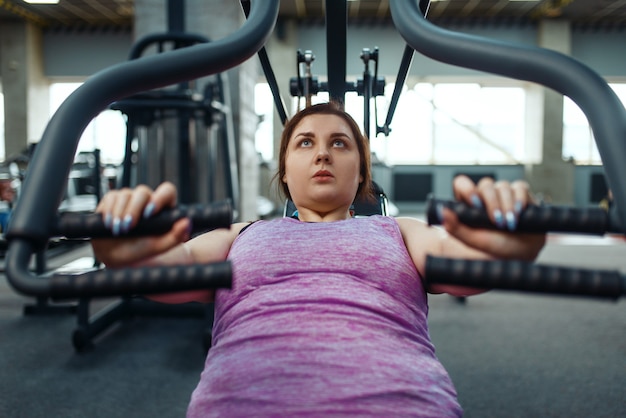 Foto mulher com excesso de peso na máquina de exercícios na academia, vista superior, treinamento ativo