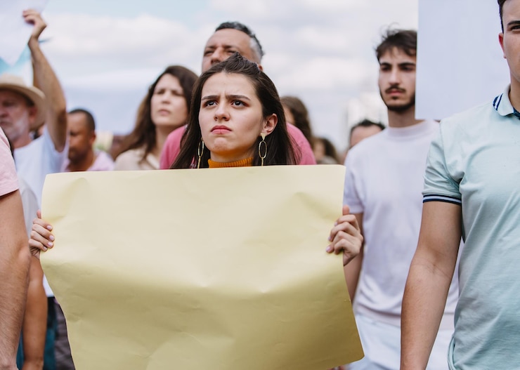 Foto mulher com expressão irritada segurando um cartaz em uma marcha de protesto