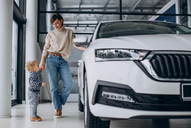 Mulher com filho bebê escolhendo um carro em um salão de carros