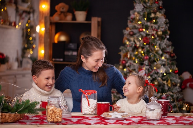 mulher com filhos em uma cozinha decorada de natal