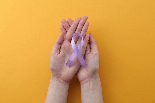 Mulher com fita de consciência violeta em fundo laranja vista superior