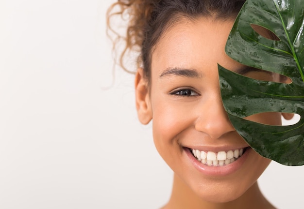 Mulher com folha fresca cobrindo metade do rosto