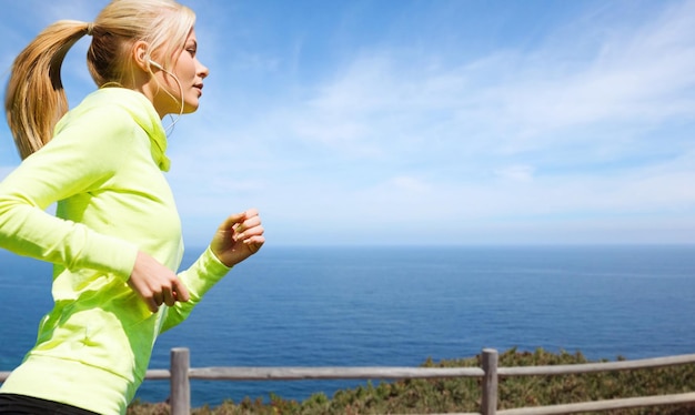 Mulher com fones de ouvido a correr à beira-mar