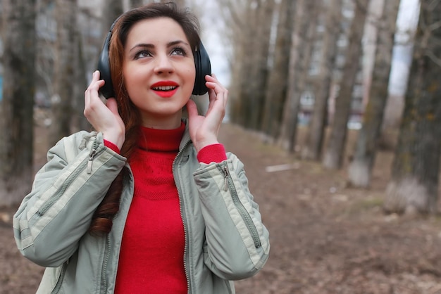 Mulher com fones de ouvido no parque outono